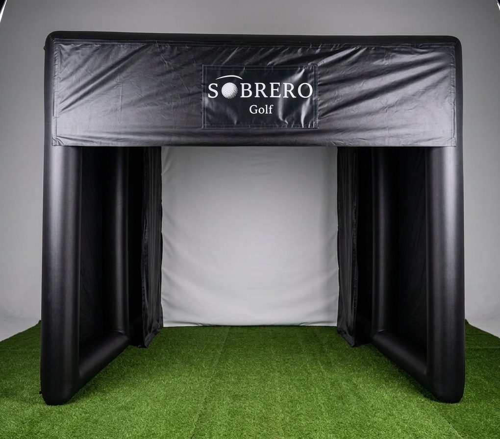 Tenda compacta da Sobrero Golf, de teto plano, com o ecrã branco ao fundo e relva no chão