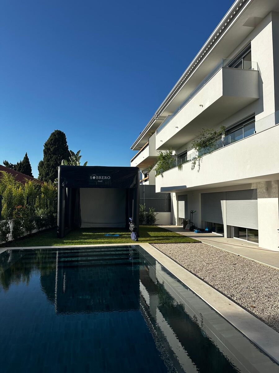 Tenda compacta da Sobrero Golf montada no jardim de uma casa, ao fundo de uma piscina